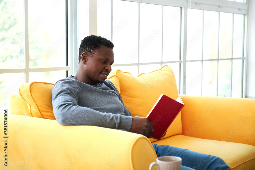 African-American man reading book at home