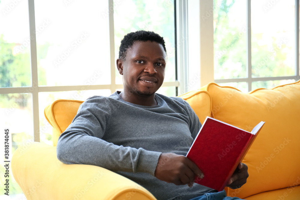 African-American man reading book at home