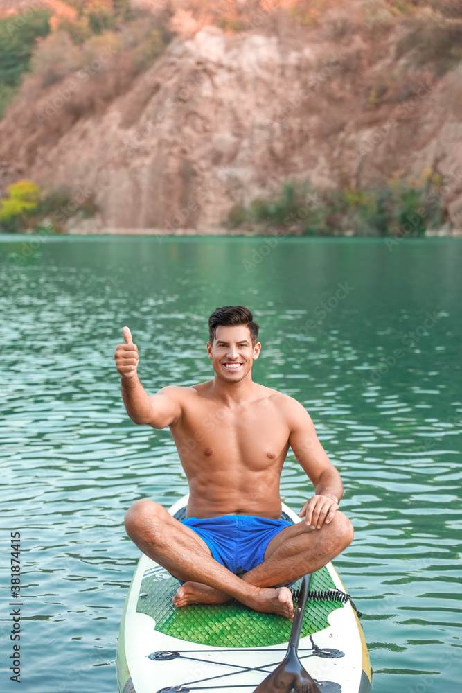 Young man using paddle board for sup surfing in river