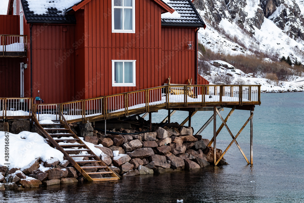 Norwegian wooden red fishing house on the seaside near the mountains