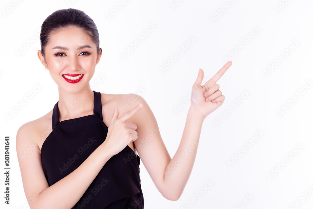 Beautiful young Asian woman pointing up to copy space and looking at camera with smile face. Glamour