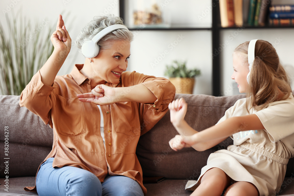 Grandmother and granddaughter dancing on sofa.