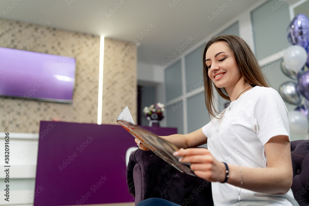 Young joyful girl waiting in reception room of beauty salon. Modern interior.