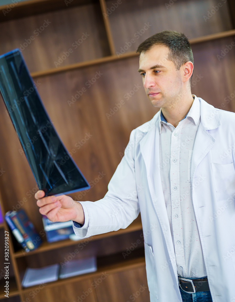 Hospital doctor holding patients x-ray film. Modern office background. Healthcare, roentgen, people