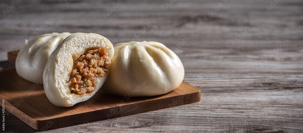 Delicious baozi, Chinese steamed meat bun is ready to eat on serving plate and steamer, close up, co