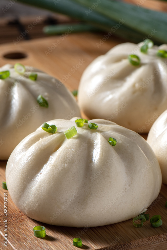 Delicious baozi, Chinese steamed meat bun is ready to eat on serving plate and steamer, close up, co