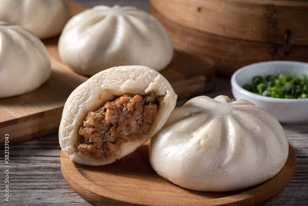 Delicious baozi, Chinese steamed meat bun is ready to eat on serving plate and steamer, close up, co