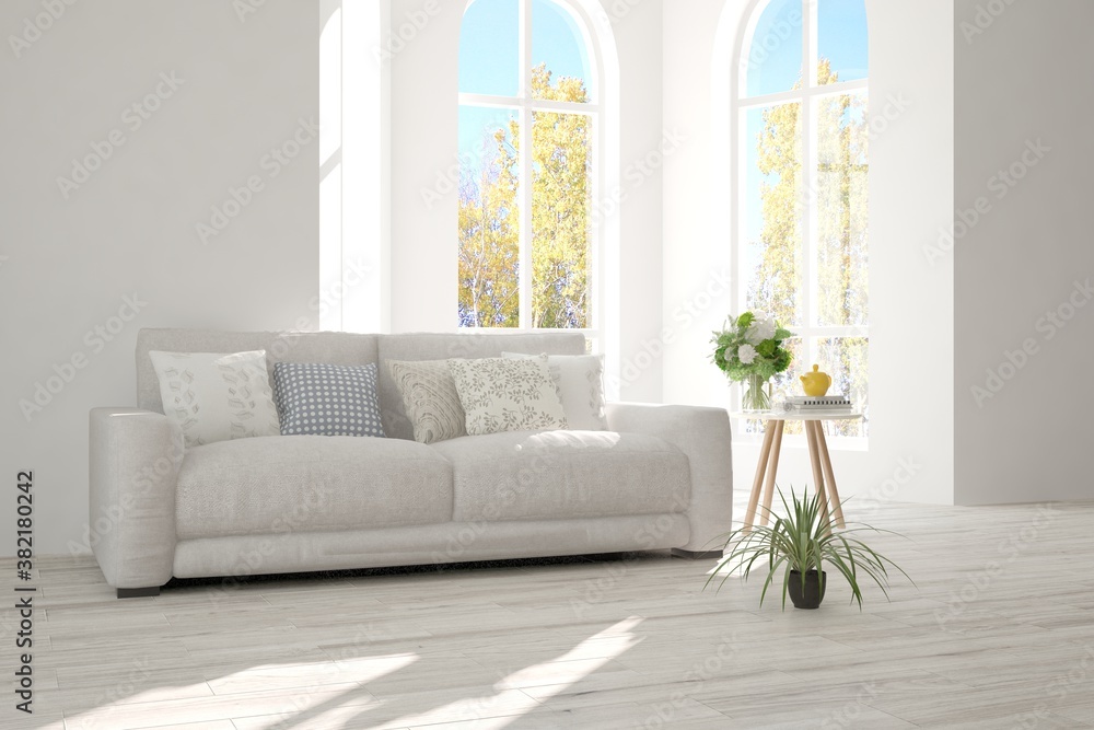 Stylish room in white color with sofa and autumn landscape in window. Scandinavian interior design. 