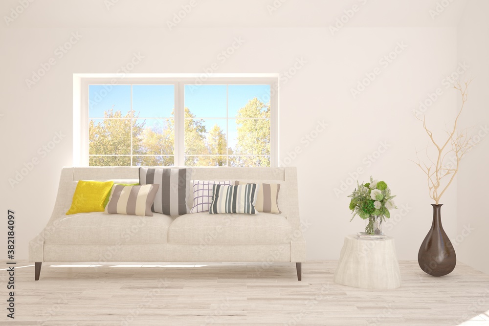 Stylish room in white color with sofa and autumn landscape in window. Scandinavian interior design. 