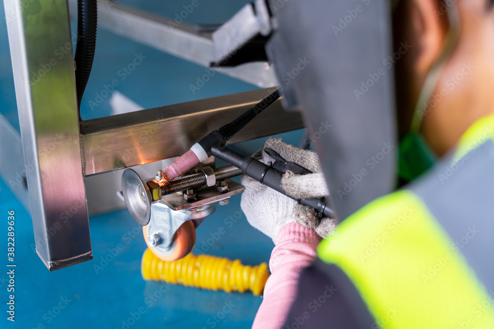 Worker welding aluminum construction a  piece of conveyer.