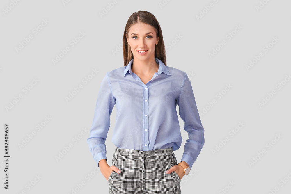 Young woman with wristwatch on light background