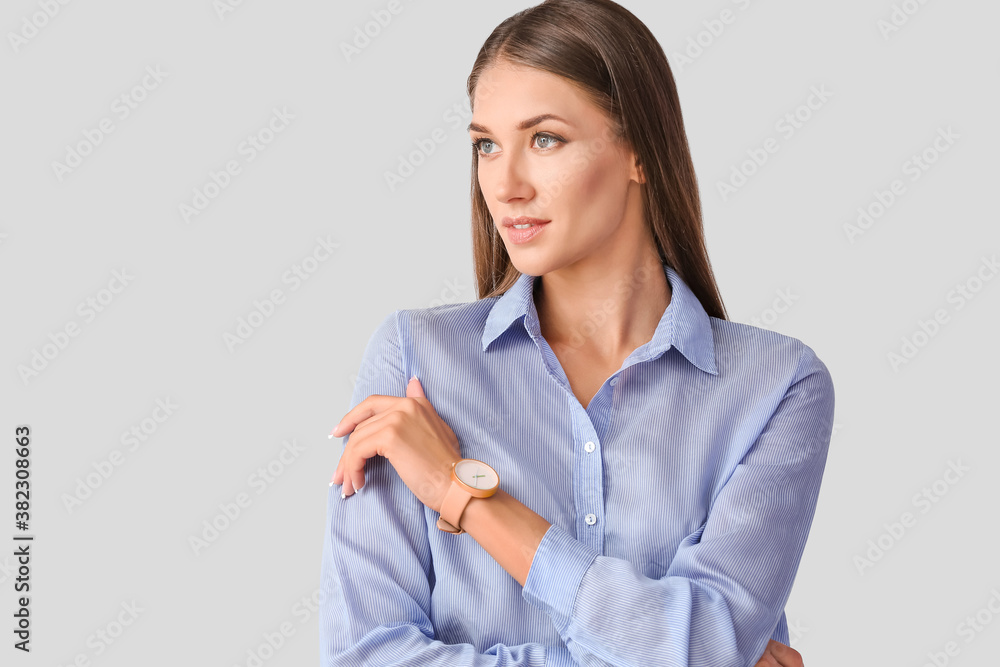 Young woman with wristwatch on light background