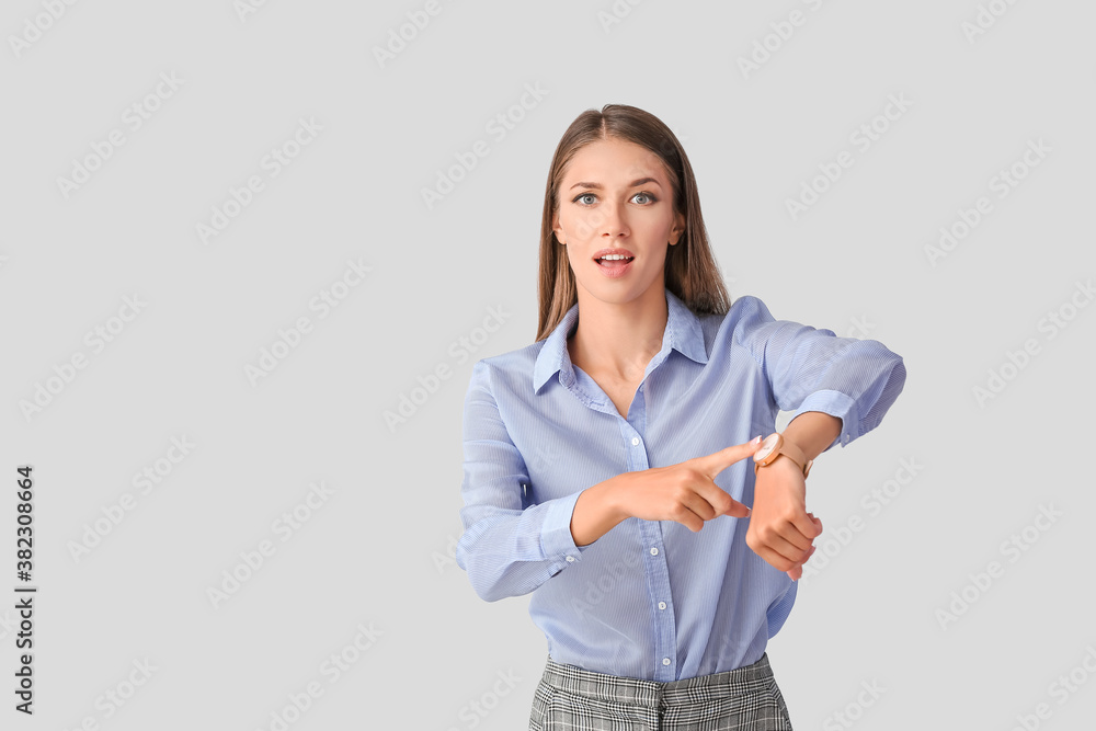 Young woman with wristwatch on light background