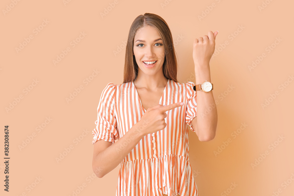 Young woman with wristwatch on color background