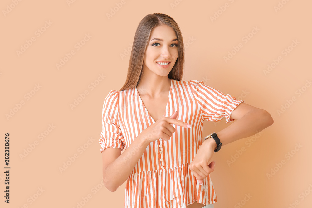 Young woman with wristwatch on color background