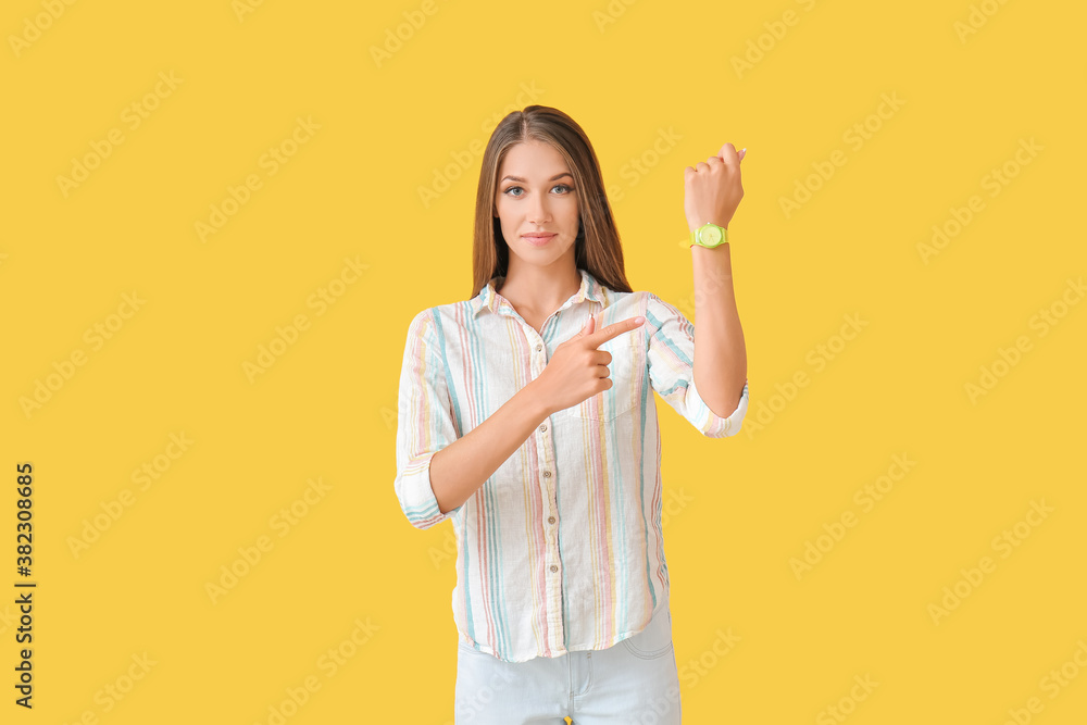 Young woman with wristwatch on color background