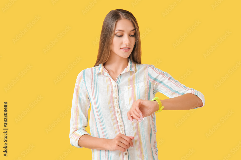 Young woman with wristwatch on color background