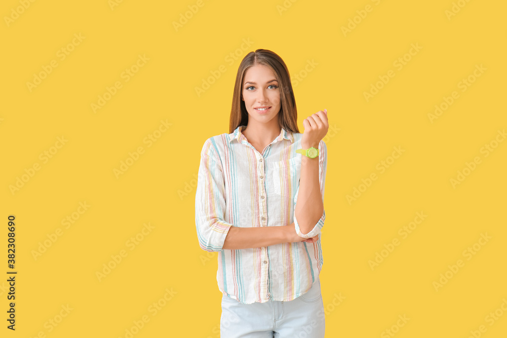 Young woman with wristwatch on color background