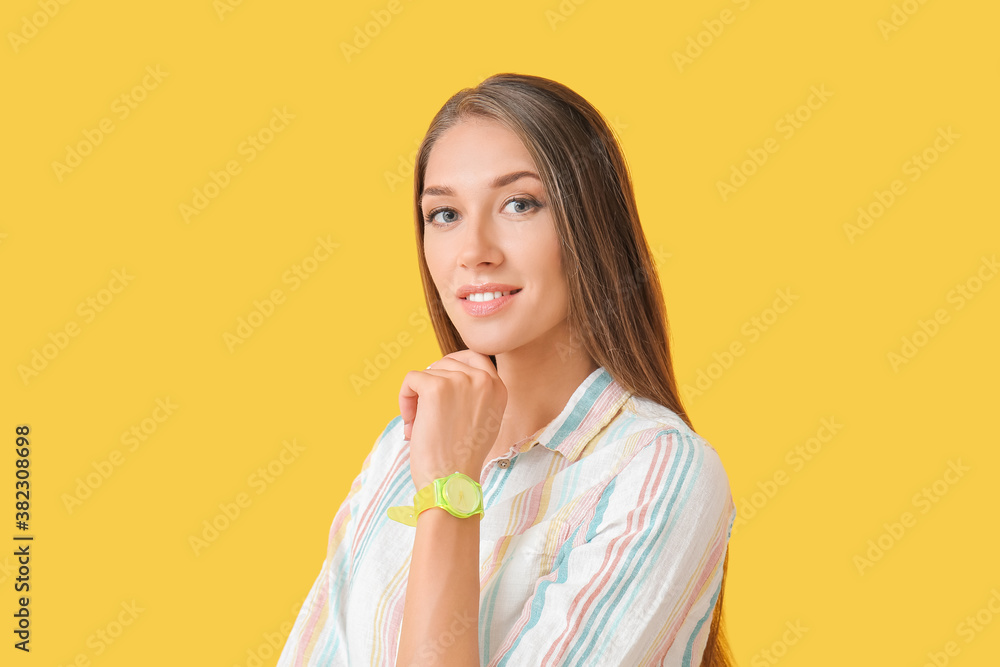 Young woman with wristwatch on color background