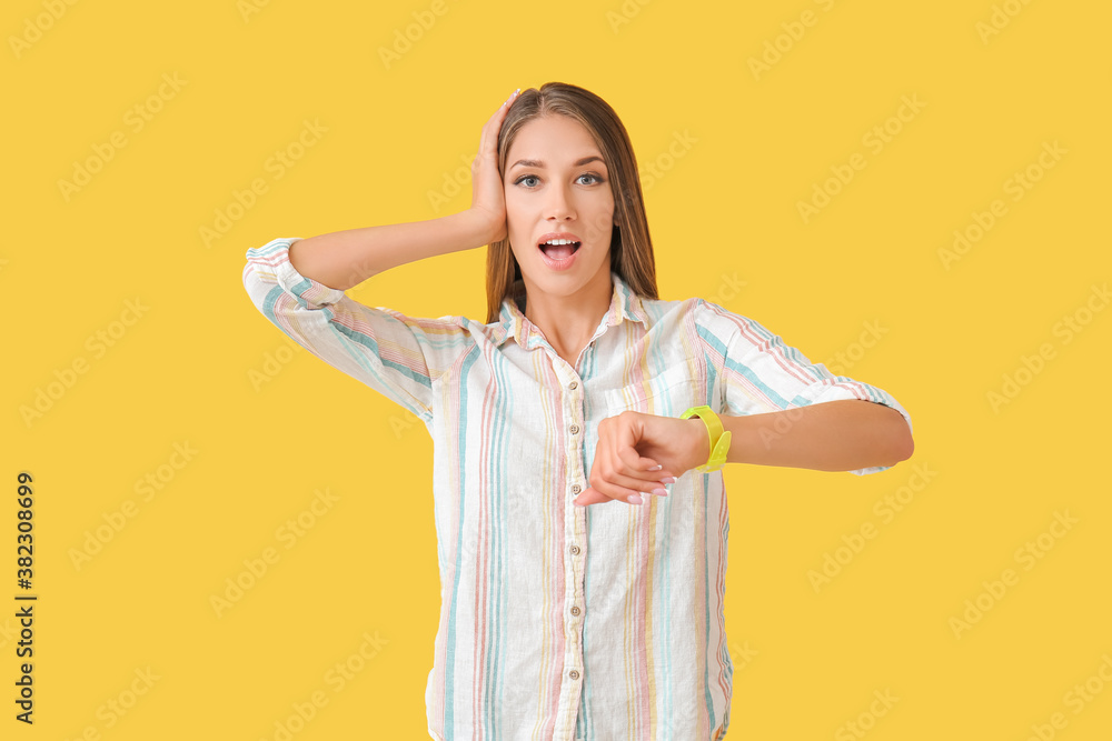 Shocked young woman with wristwatch on color background