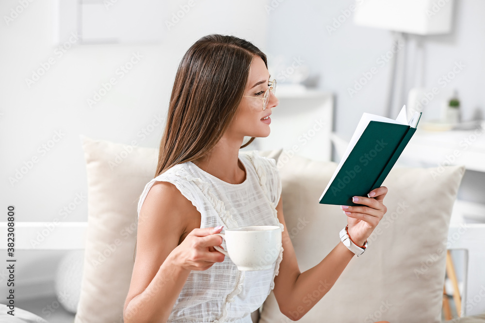 Beautiful young woman reading book at home