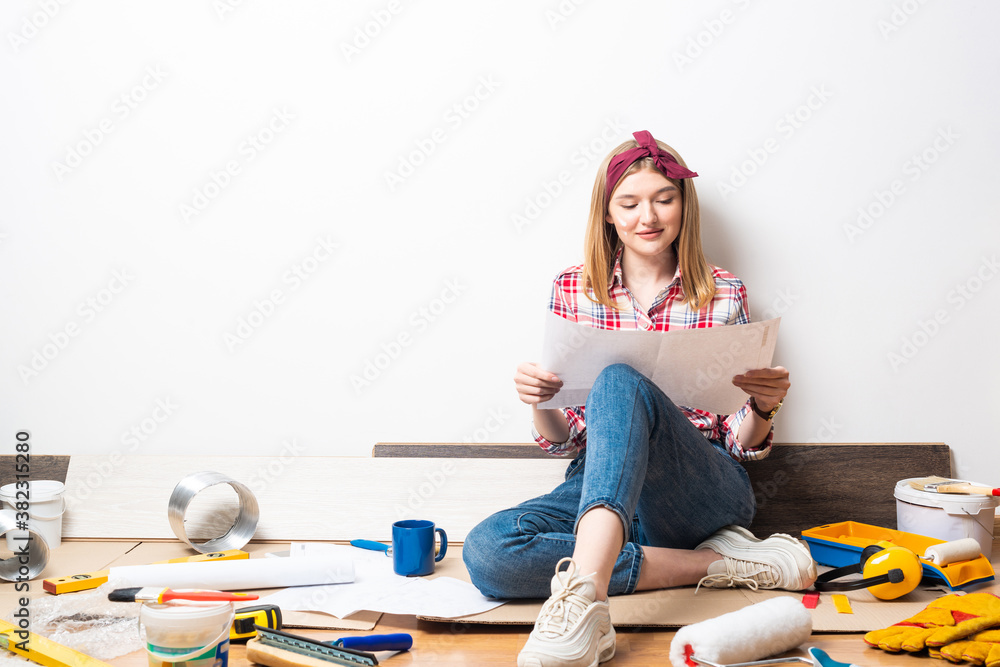 Smiling girl sitting on floor with blueprint