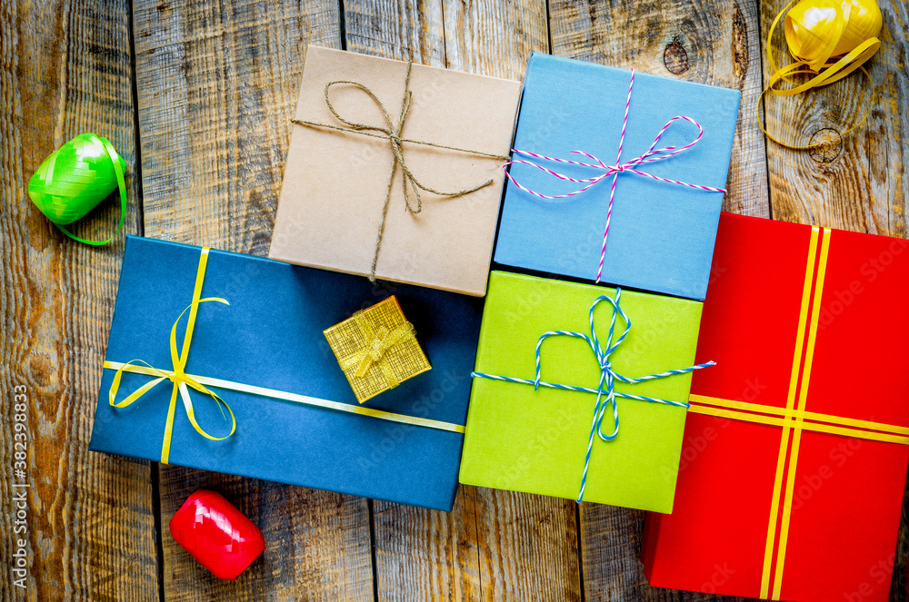 Colored gift boxes on wooden background with ribbon and straw