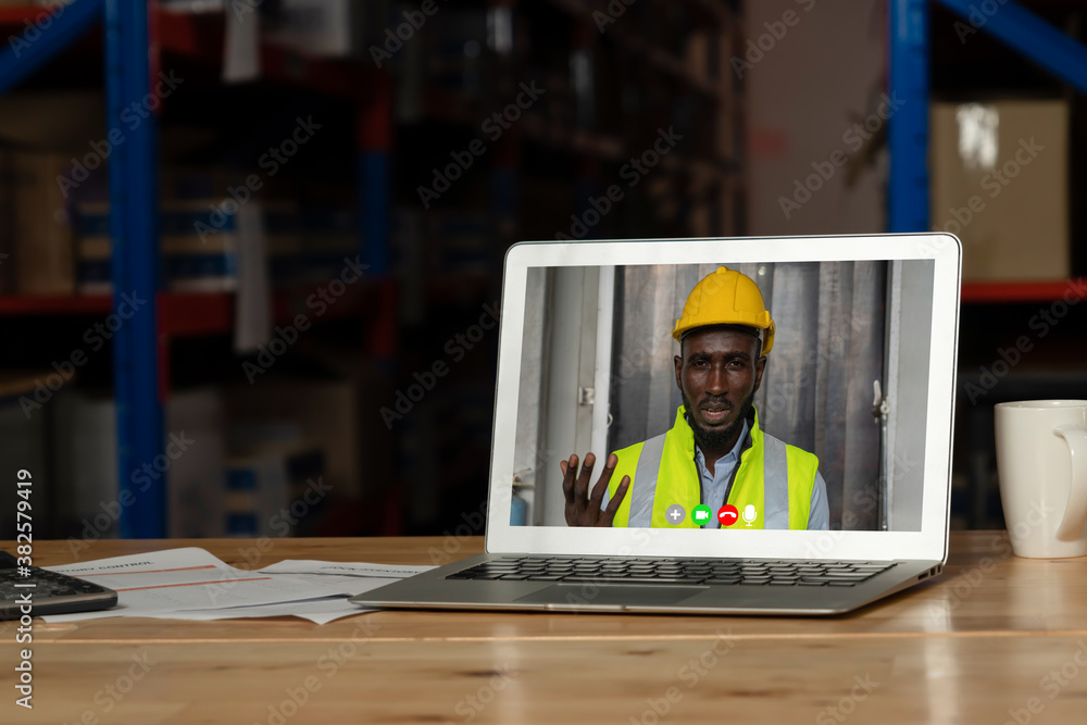 Warehouse staff talking on video call at computer screen in storage warehouse . Online software tech