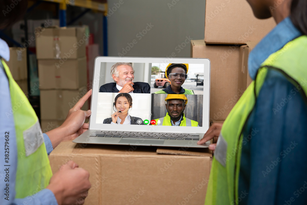 Warehouse staff talking on video call at computer screen in storage warehouse . Online software tech