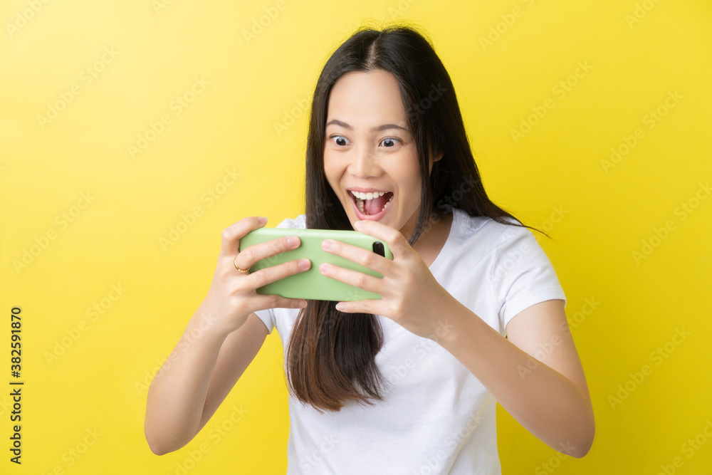 Beautiful Asian woman. She feels shocked with the phone on a yellow background.