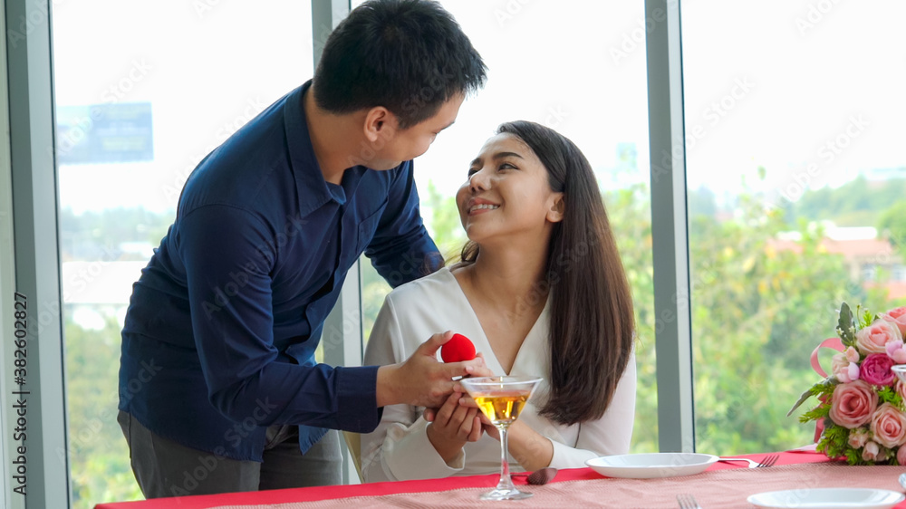 Romantic couple giving gift to lover at restaurant . Happy couple lifestyle .