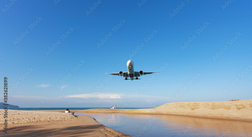 Commercial airplane landing above sea in summer season and clear blue sky over beautiful scenery nat