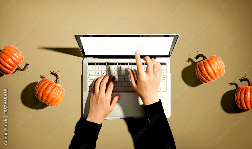 Autumn pumpkins with person using a laptop computer from above