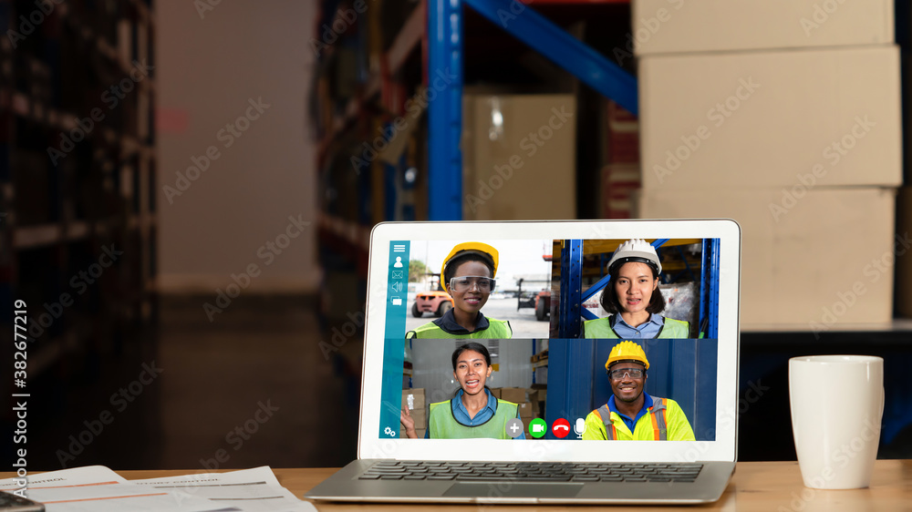 Warehouse staff talking on video call at computer screen in storage warehouse . Online software tech