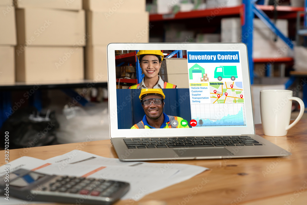 Warehouse staff talking on video call at computer screen in storage warehouse . Online software tech