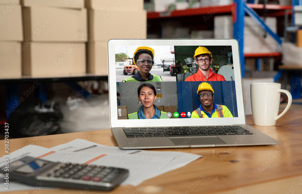 Warehouse staff talking on video call at computer screen in storage warehouse . Online software tech