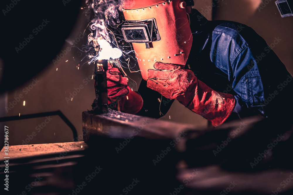 Metal welding steel works using electric arc welding machine to weld steel at factory. Metalwork man