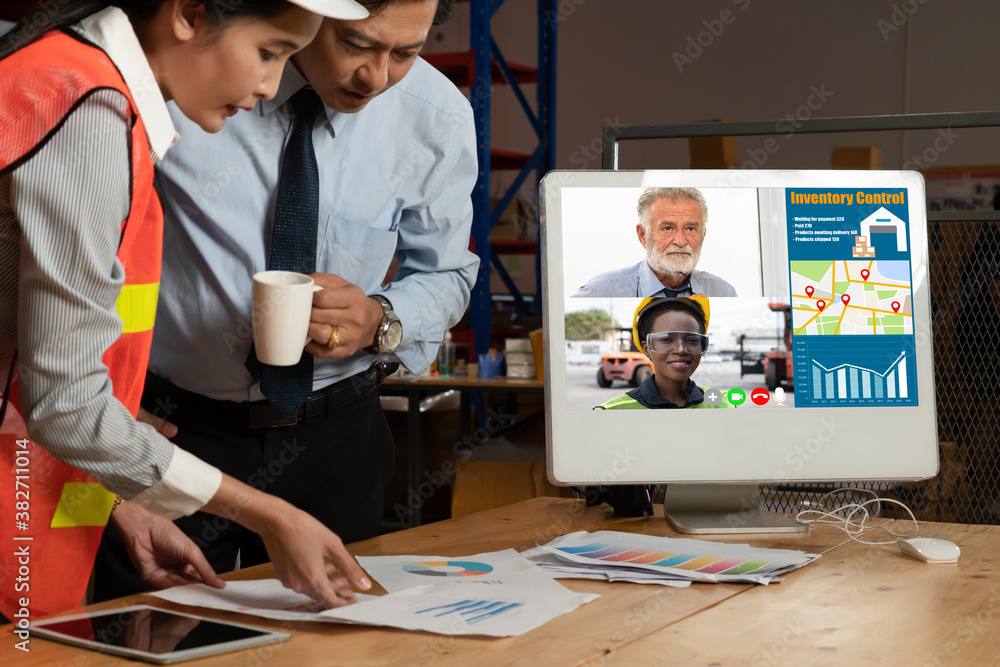 Warehouse staff talking on video call at computer screen in storage warehouse . Online software tech