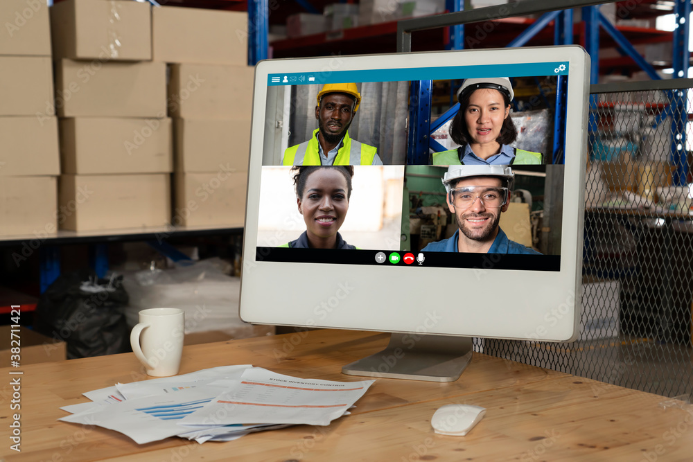 Warehouse staff talking on video call at computer screen in storage warehouse . Online software tech