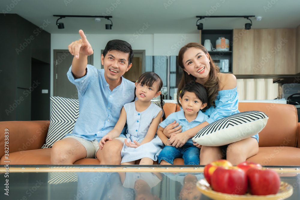 Asian happy family sitting and watching television in living room at home and spent quality time tog