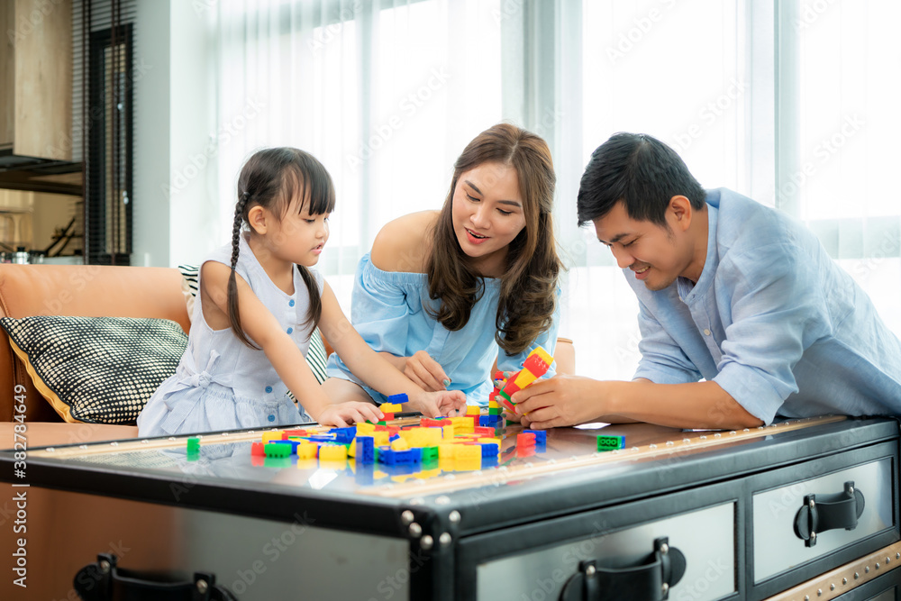 Asian family spends time in playroom with father, mother and daughter with toys on room background b