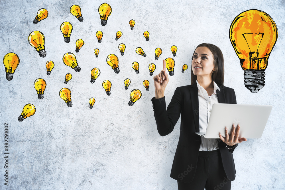 Young businesswoman holding laptop with creative lightbulb sketch