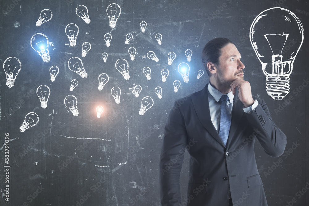 Young european businessman with creative lamps sketch on blackboard.