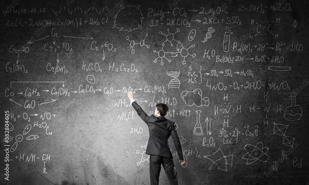 Scientist writing formulas on chalkboard