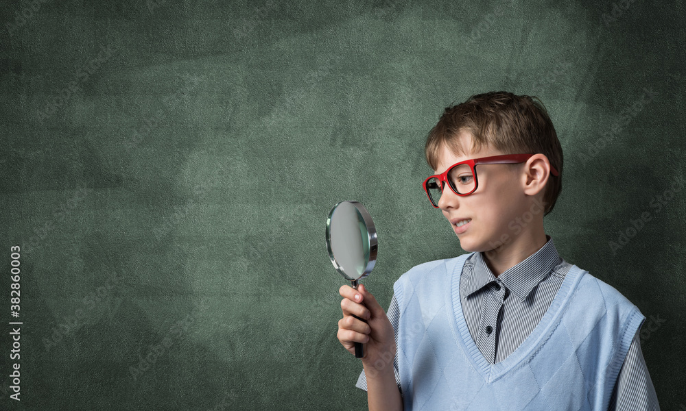 Curious school boy with magnifier