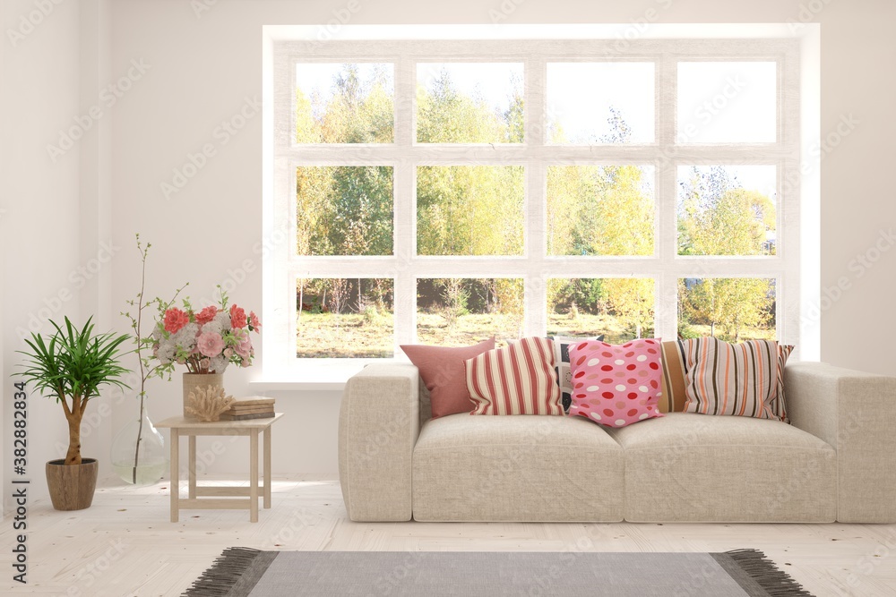 Stylish room in white color with sofa and autumn landscape in window. Scandinavian interior design. 