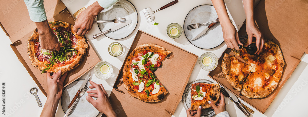 Pizza party for friends or family. Flat-lay of various pizzas, lemon drinks and peoples hands over w