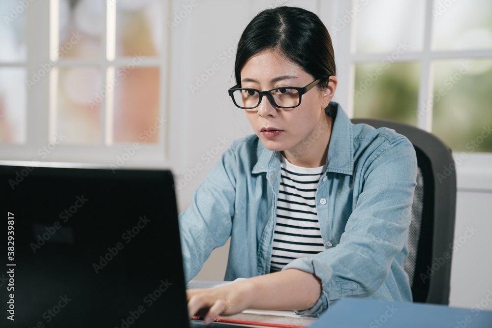 微笑的女学生在家里用笔记本电脑学习。戴眼镜的女青少年在打不