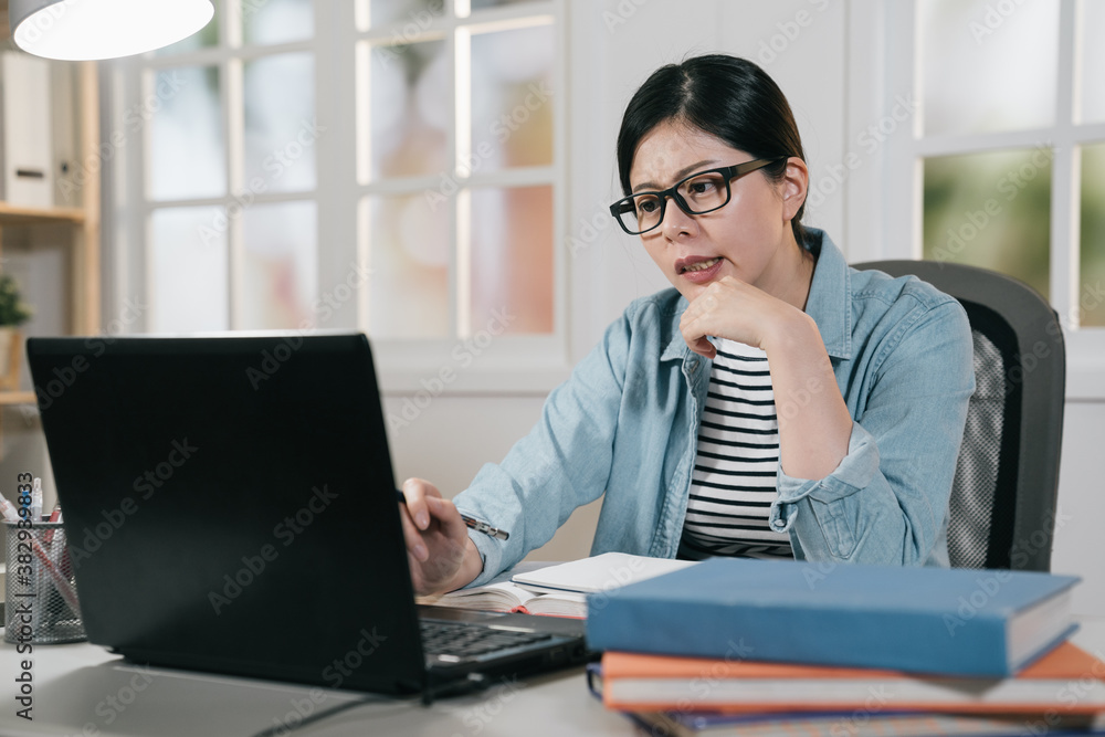 attractive asian korean female university student using laptop in house. pensive young college girl 