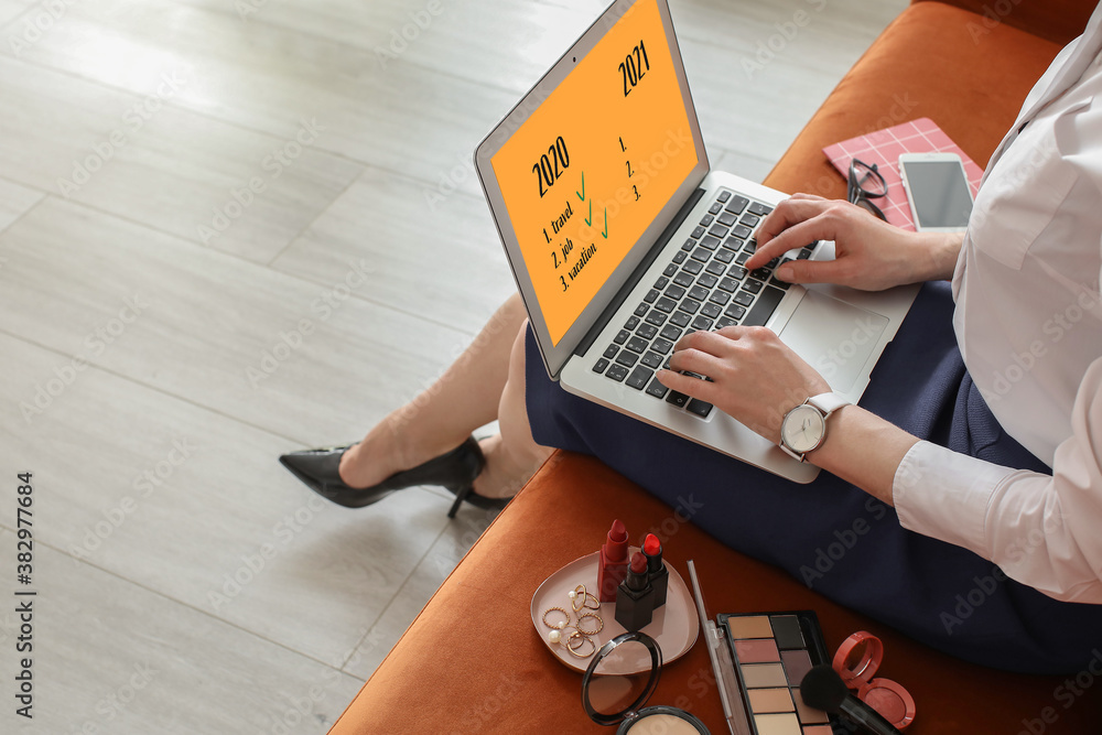 Female makeup artist with laptop making to do list at home